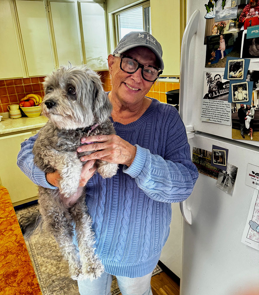 Kristin Myers holding small dog while standing in a kitchen.