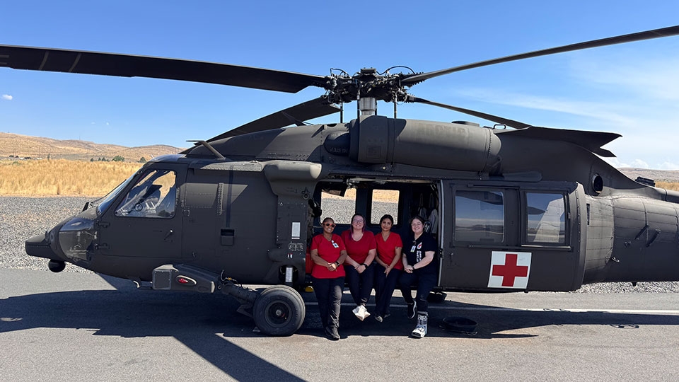 Red Cross staff standing beside a military helicopter.