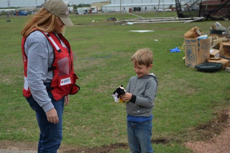  Harrison Thralls, 6, admires a Mickey Mouse plush toy given to him by Red Cross disaster worker Cristal Mitchell. Harrison and his parents drove an hour to help his grandmother clean up her brother’s home after it was hit by a tornado.