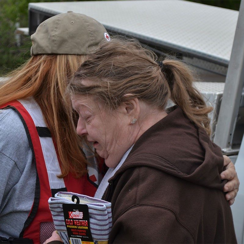 Volunteer Cristal Mitchell comforts Carolyn Wiseman outside her damaged home.