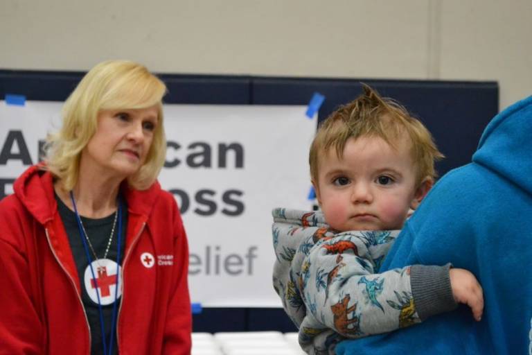 Disaster Mental Health volunteer Liz Marmon speaks to Michael McCray at a resource center in Shawnee, Oklahoma, while he holds his 14-month-old son, Colton.