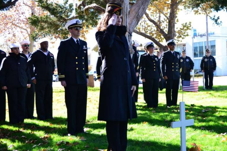 VFW Post 8706 Cmdr. and Red Cross volunteer Rebecca McGary salutes after placing a U.S. flag on the cross marking a symbolic grave at the Pearl Harbor Remembrance Day ceremony in Oklahoma City.