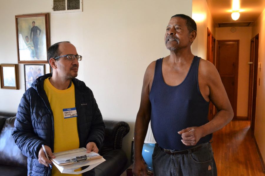 Volunteer Marcelo Souza (left) goes over home fire info with Norman Powdrill. The retired Vietnam veteran and his wife, Lucille, did not have smoke alarms in their home when the Red Cross visited.
