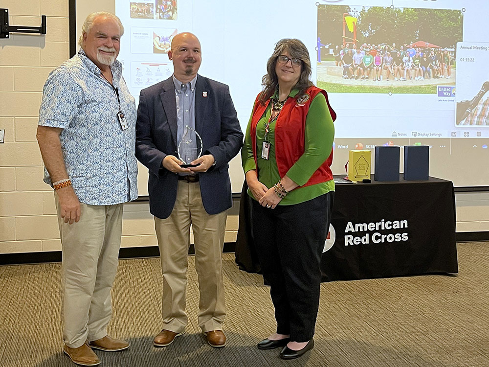Dennis and Angela Wilhite standing next to interim SAF Director Dean Epley who's holding a Red Cross award.