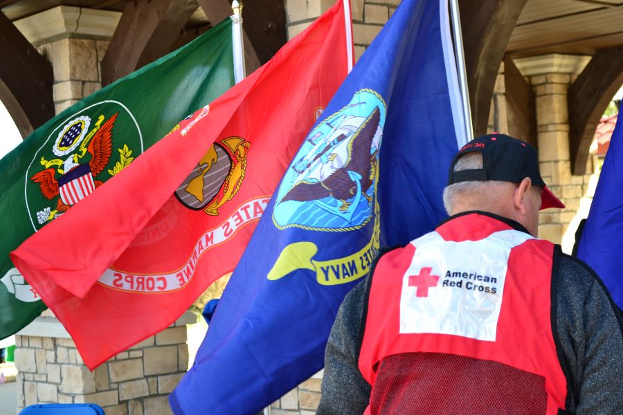 man in red cross vest facing flags