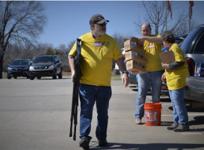 volunteers holding chairs and boxes