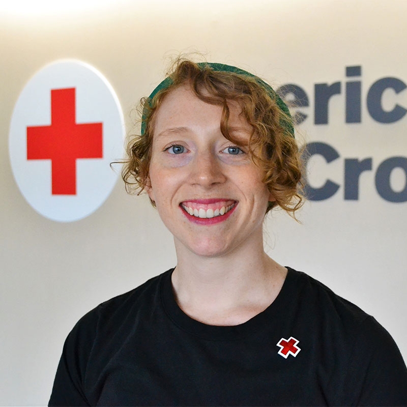 Red Cross employee Colleen Mansur headshot with Red Cross logo in background.