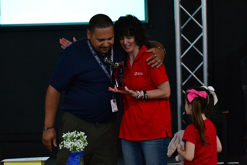 Kate Collins receiving the Clara Barton Award from Community Disaster Program Manager Karvin Vega while her daughter looks on.
