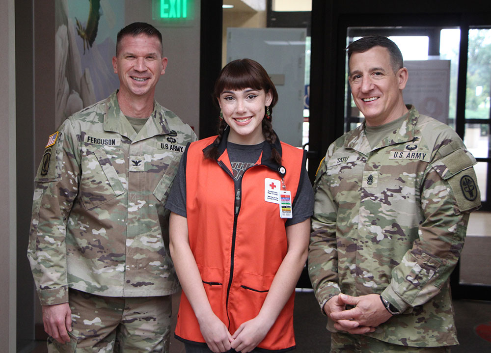 Red Cross VolunTEEN Rinoa Fraley poses for a photo with RAHC Commander Col. Jason Ferguson and RAHC Command Sergeant Major Command Sgt. Maj. Michael Tatu.