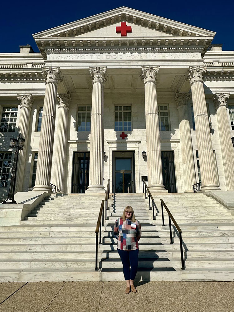 Tara Burnett standing at the bottom of stairs in front of the Washington, D.C. Red Cross building.