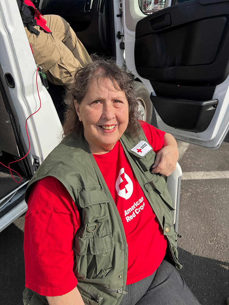 red cross volunteer Julia Bishop sitting next to a red cross van.