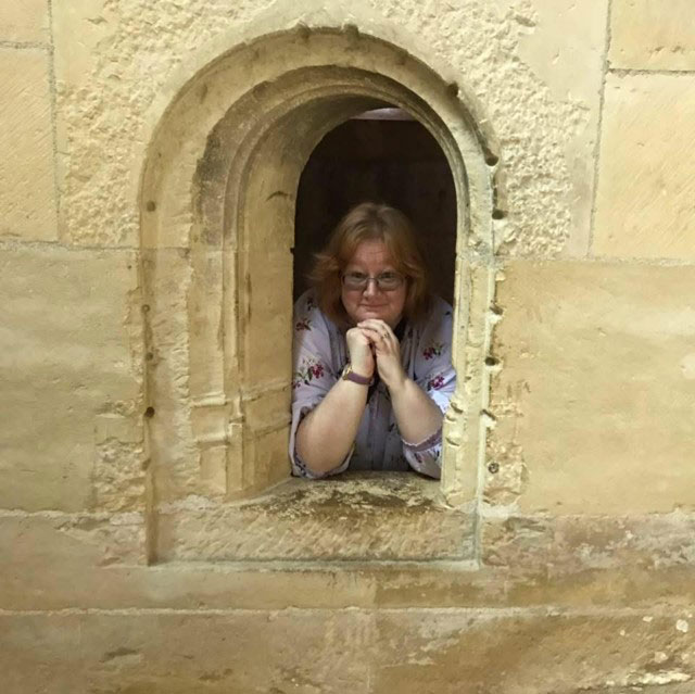 Amanda Swinford looking out of a stone building window.