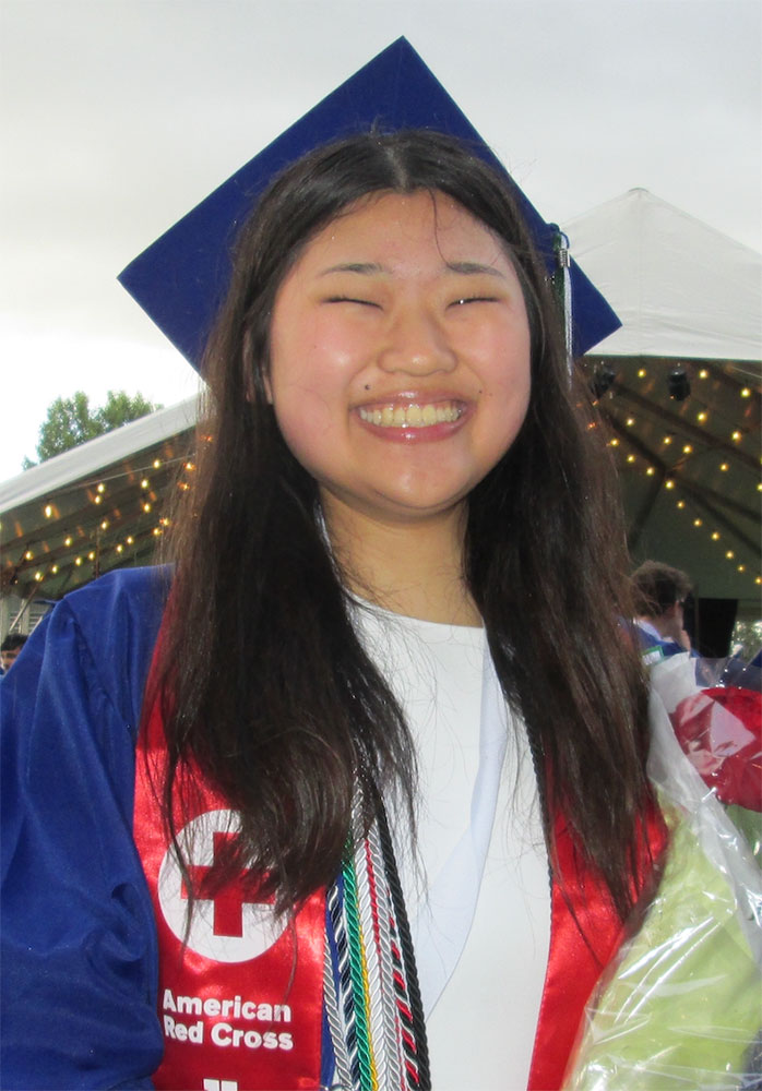 Ayu Kira smiling while wearing her graduation cap and gown.