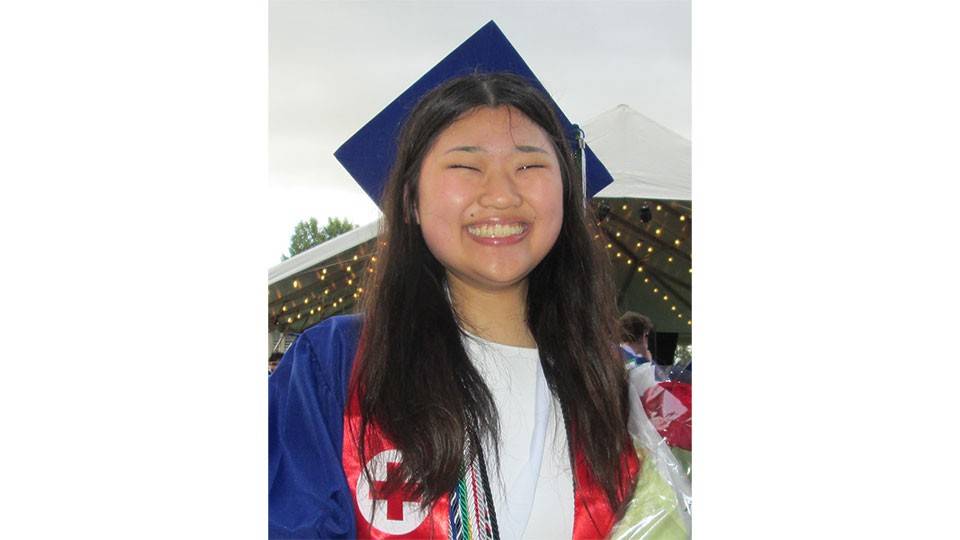 Ayu Kira smiling while wearing her graduation cap and gown.