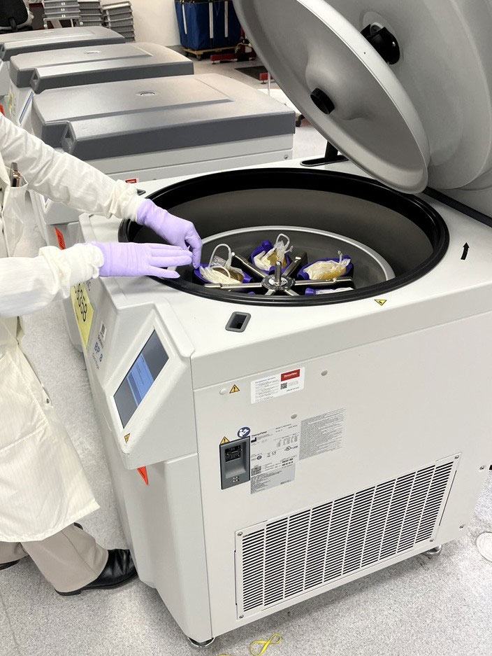 a lab worker wearing a white lab coat and gloves working in a lab on a laboratory machine.