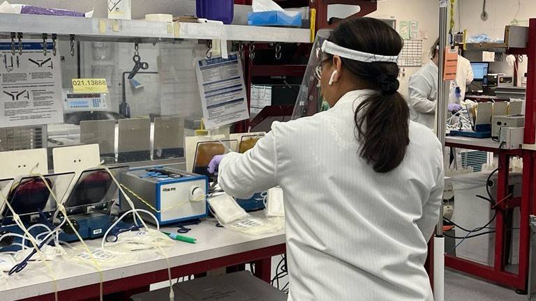 a lab worker wearing a white lab coat working in a lab.