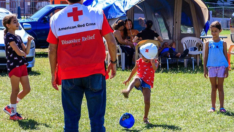 Children playing a game of soccer with a mental health volunteer.