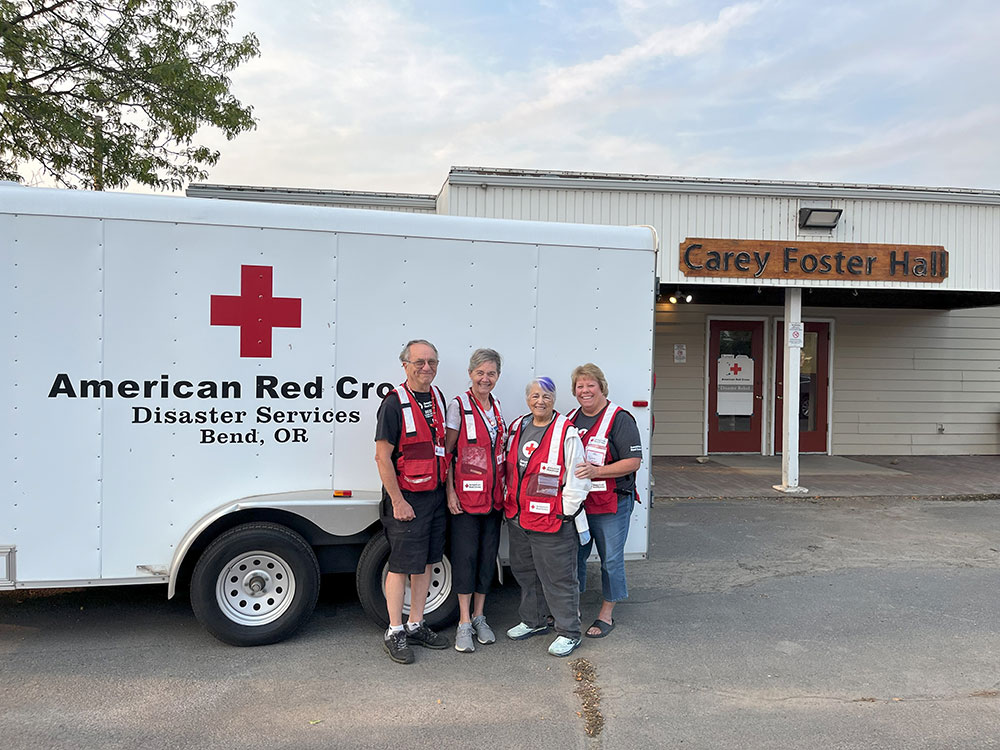 Four Red Cross volunteers standing next to an Disaster Dervices trailer.
