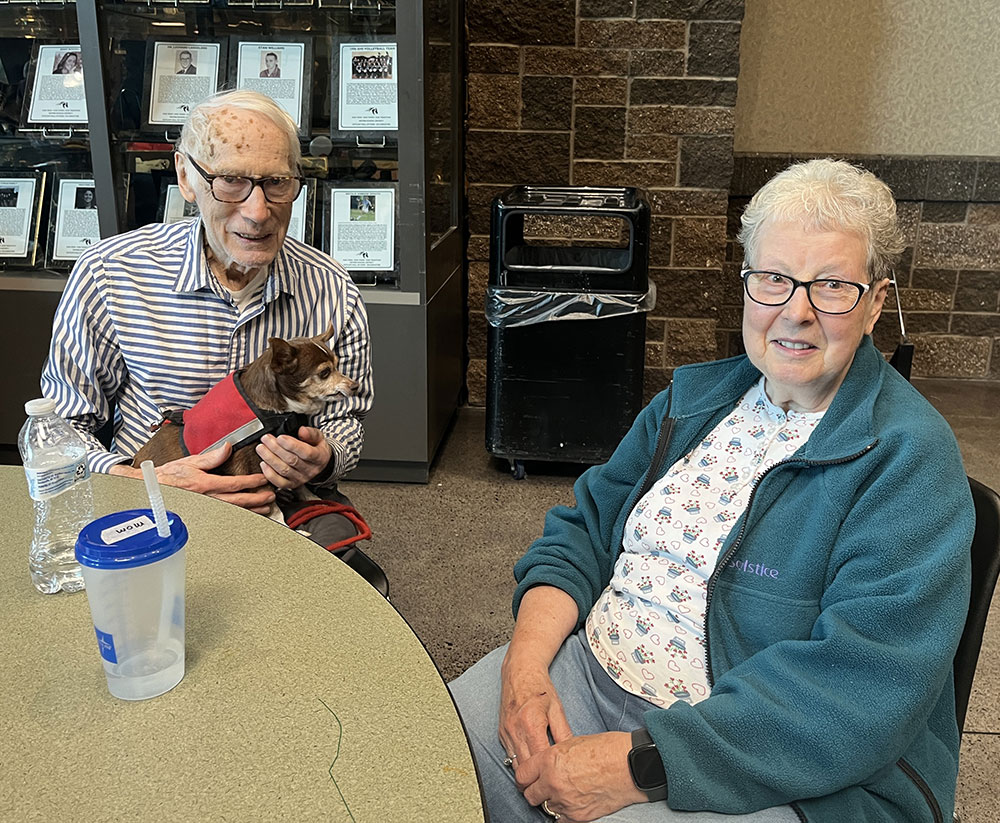 Darold and Marylee Dilley sitting at a table in a Red Cross shelter while holding their small dog.