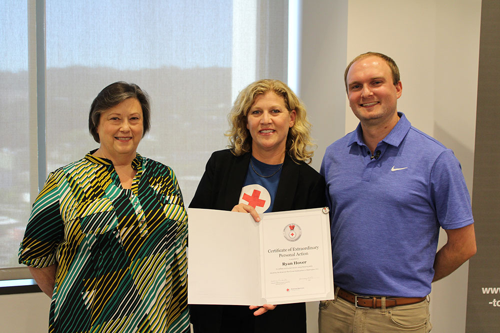 Deanna Premo and Ryan Hover stand next to Red Cross Comms Director Rebecca Marshal who's holding a lifesaving award.