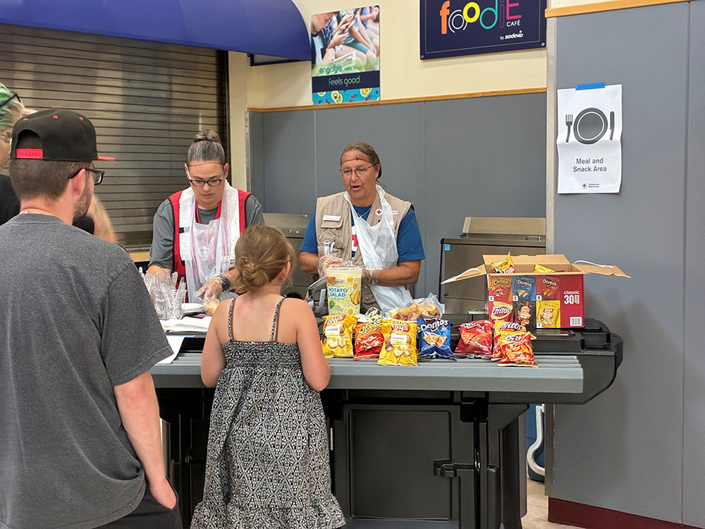 two Red Cross volunteers serving food in a Red Cross shelter.