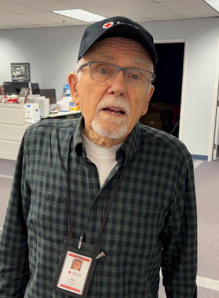 Jim Stevenson, wearing a Red Cross hat and glasses, smiles for picture.