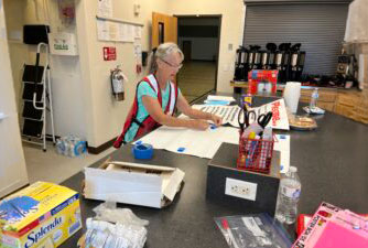 a Red Cross volunteer working on paperwork at a table.