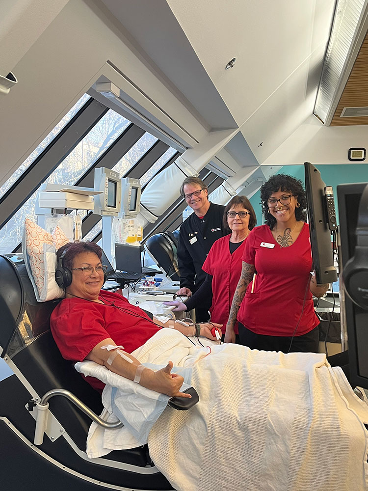 Lynn Sivaivai donating platelets at the newly renovated Portland Blood Donor Center with phlebotomist friends beside her.