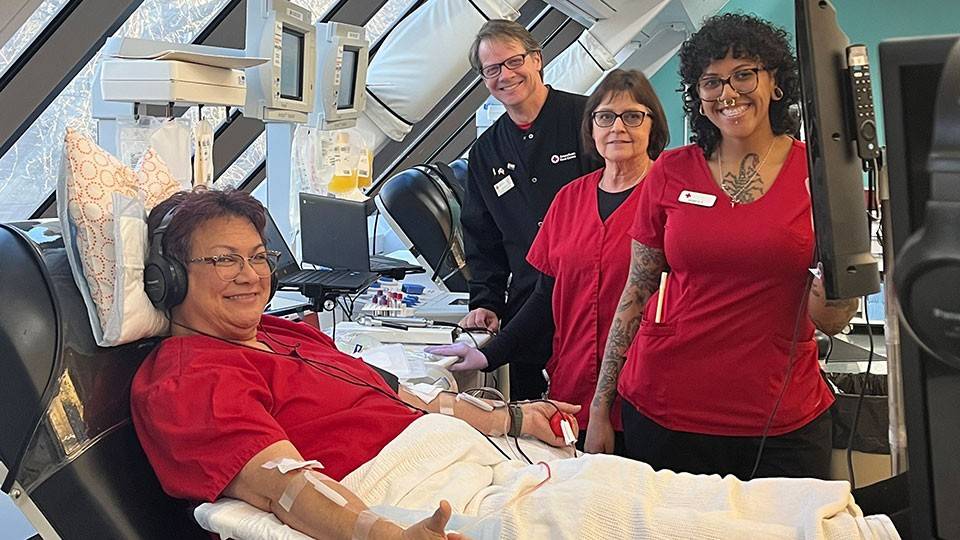 Lynn Sivaivai donating platelets at the newly renovated Portland Blood Donor Center with phlebotomist friends beside her.