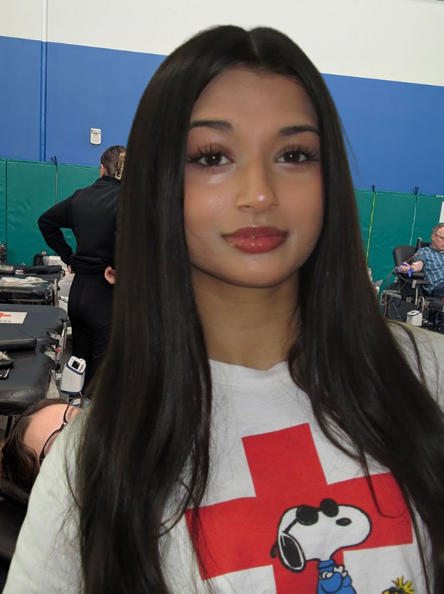 Maya Iyer, with long hair, wearing a Red Cross snoopy shirt.
