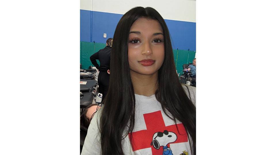 Maya Iyer, with long hair, wearing a Red Cross snoopy shirt.