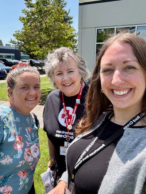 Outside an office building group photo of Service to the Armed Forces Director Meghan Hahn, Jana Norton, Service to the Armed Forces Manager Jessica Pomeroy.