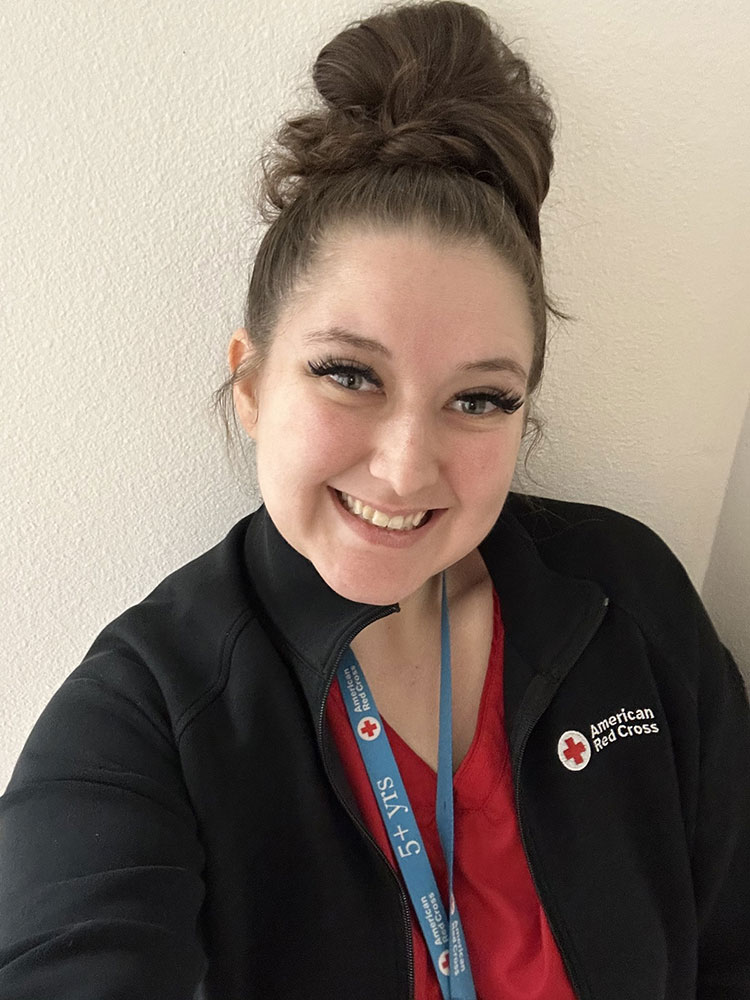 Brianna Buchanan wearing a Red Cross jacket and lanyard, takes a selfie.