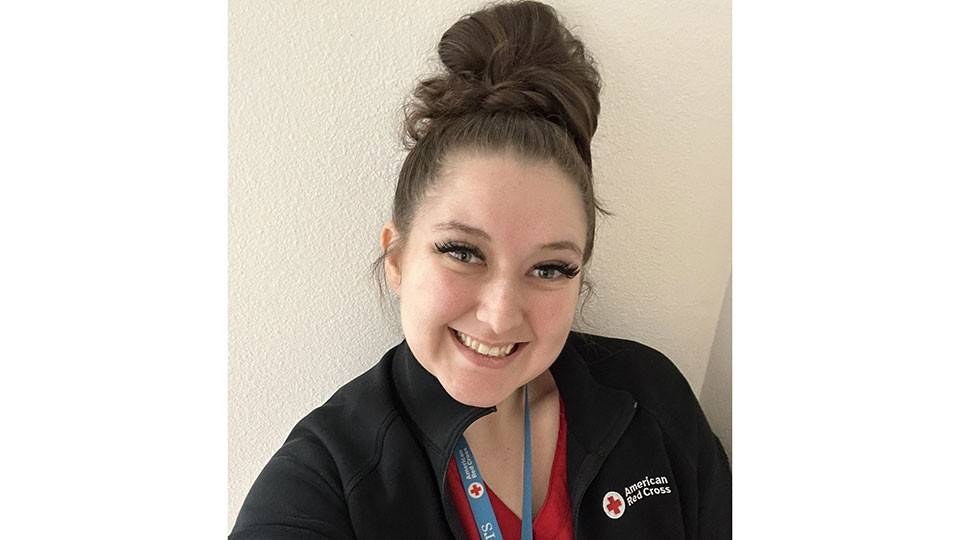Brianna Buchanan wearing a Red Cross jacket and lanyard, takes a selfie.