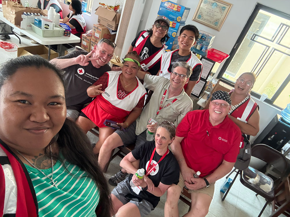 A group of Red Crossers smiling and posing together for a photo in a well-lit room with colorful decorations.