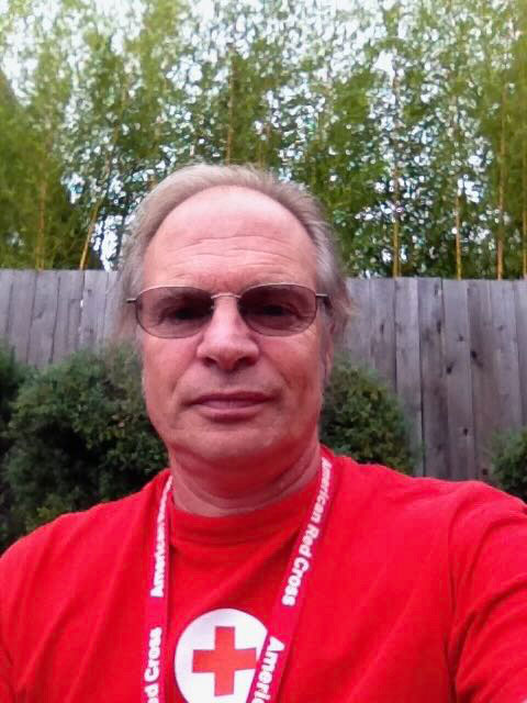 Robert Cork, wearing a Red Cross shirt and lanyard, takes a selfie.
