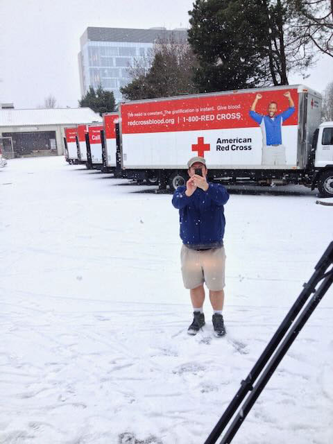 Robert Cork standing outside in the snow with a row of Red Cross moving trucks parked behind him.