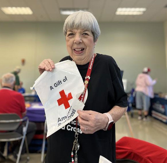 elderly lady holding up a Red Cross gift bag.