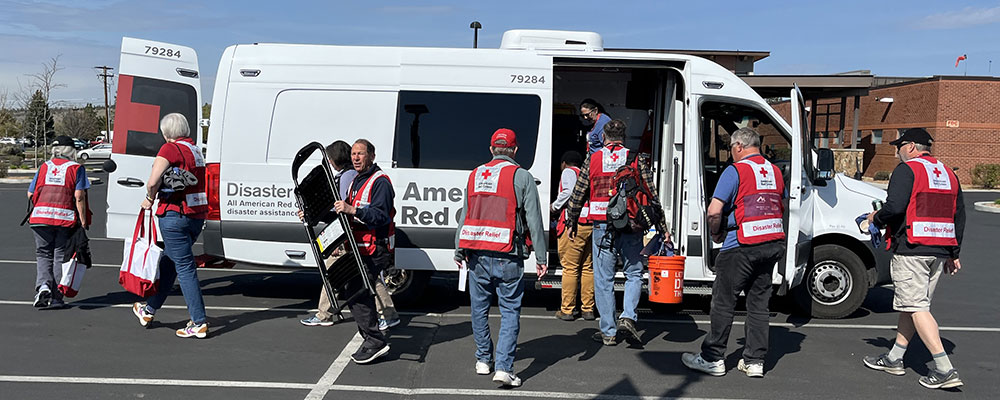 Red Cross volunteers grabbing equipment to install smoke alarms from a Red Cross vehicle.