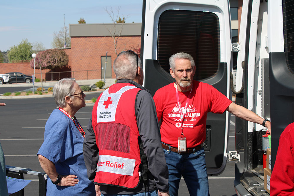 Red Cross volunteers standing at the back of a Red Cross vehicle.