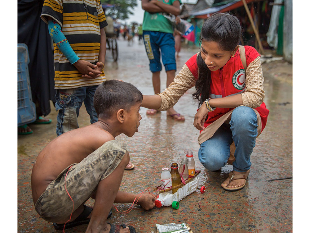 A woman assists a boy in playing with a toy.