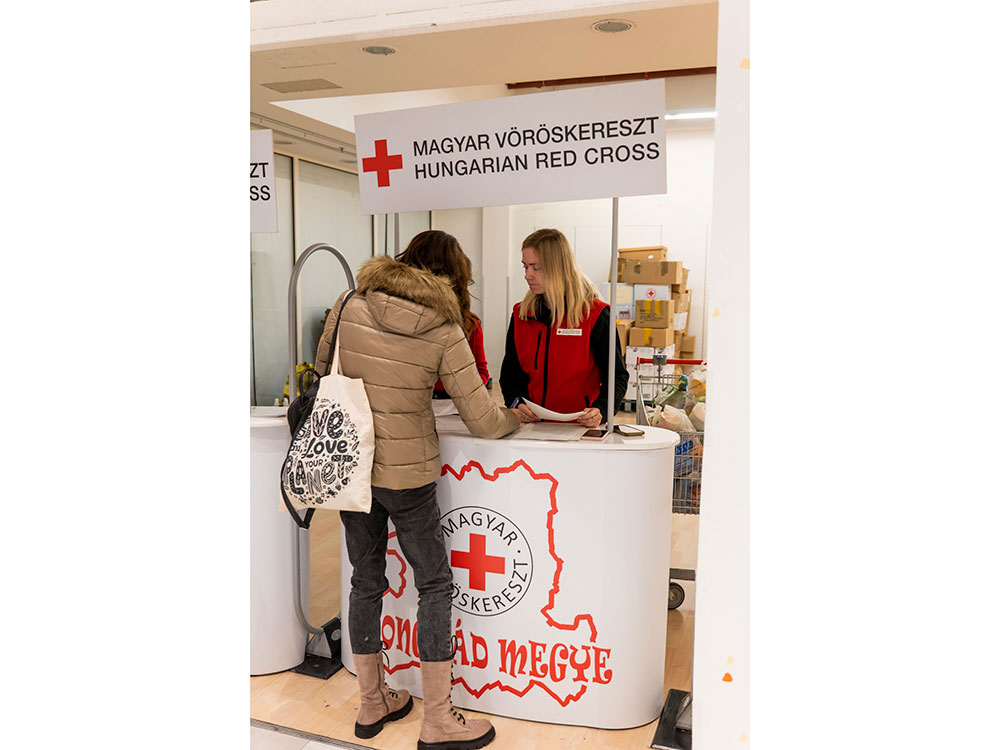 A Finnish Red Cross worker helping a person at a Red Cross booth.