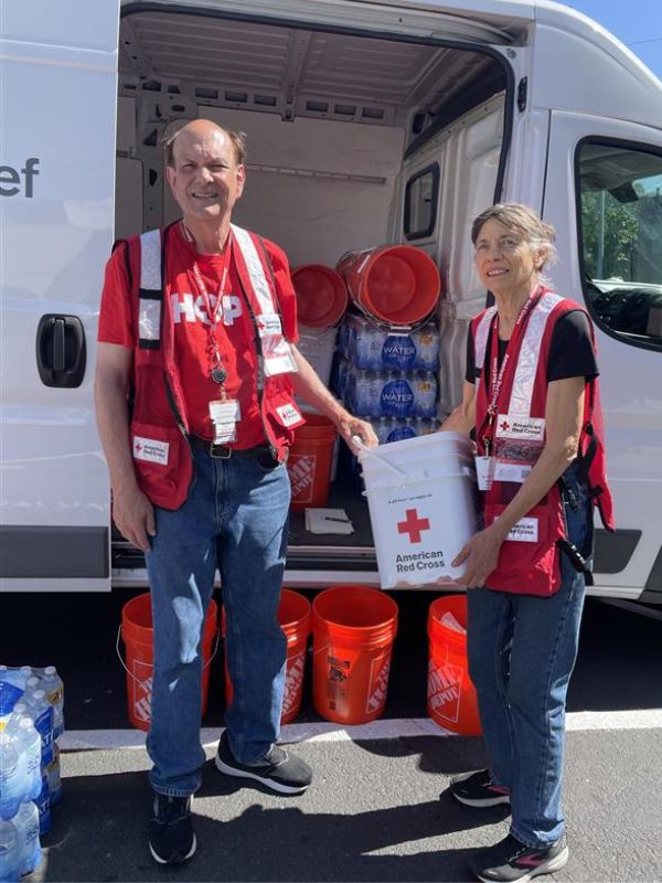 volunteers bruce and ellen holding red cross bucket