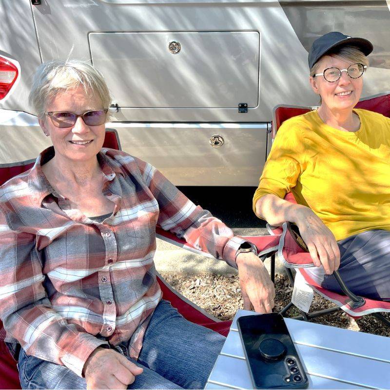 two women sitting outside of van