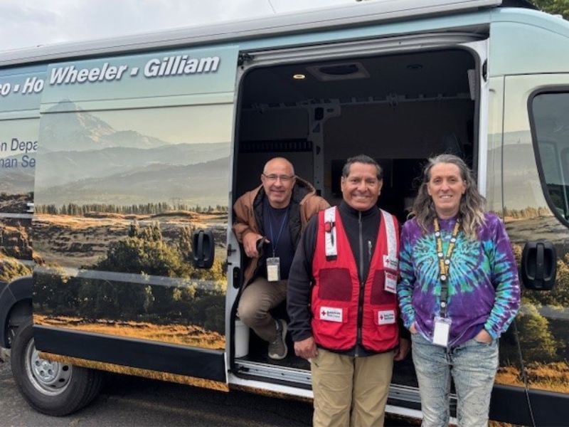 roman perez and volunteers standing outside of van.