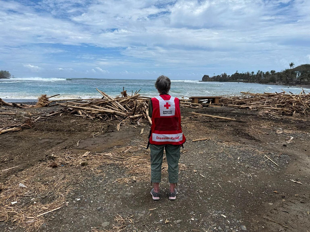 Red Cross volunteer Melody Actouka at Humatak Bay in Guam looking at the debris on the ground.