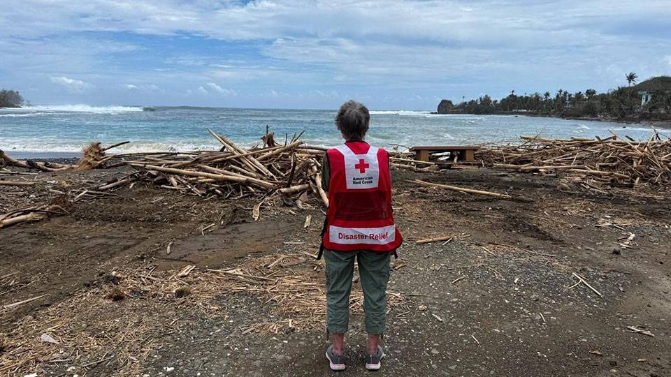 Red Cross volunteer Melody Actouka at Humatak Bay in Guam looking at the debris on the ground.