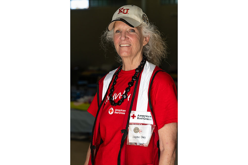 Jayne Dey smiling wearing a beige cap and a Red Cross vest with a name tag.