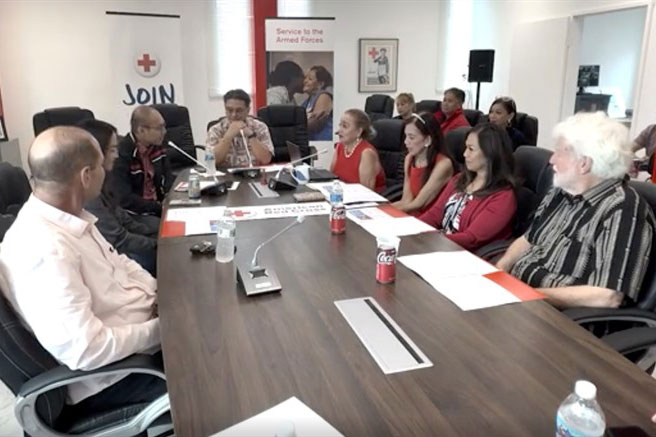 group of people sitting at a conference table speaking to each other.