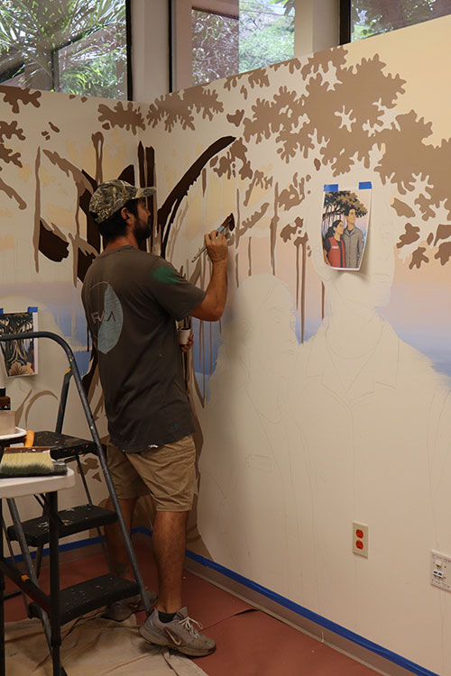 Jeff Gress in the process of painting the mural on the inside wall of a Red Cross building.